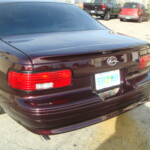 Before and after photographs of a damaged Chevy Impala that was repaired by Elite Paint & Body Shop in West Palm Beach, Florida.